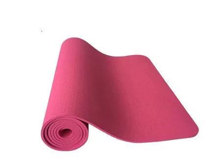 6mm TPE beginner yoga mat in black, rolled on wooden floor with textured non-slip surface visible