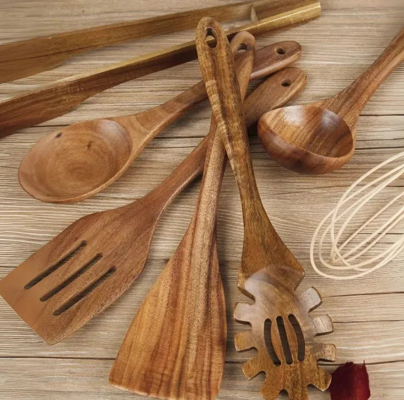 Natural wood 7-piece cooking utensil set for non-stick pans on a kitchen counter.