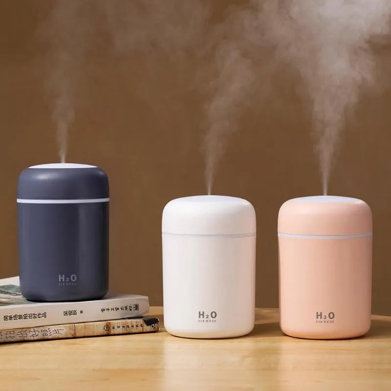 Pink, white, or navy blue USB mini humidifier with colourful lights on a desk