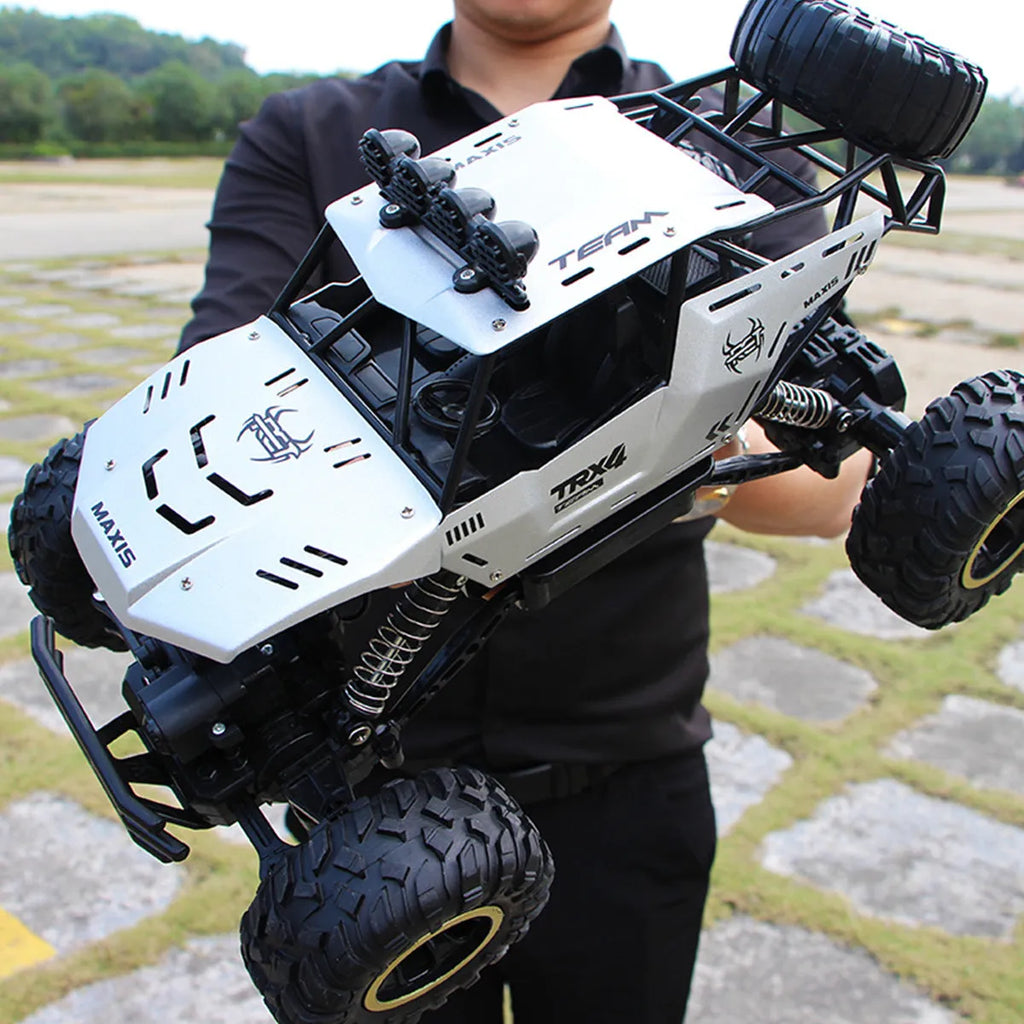 Black and silver remote control off-road car on rough terrain showing four-wheel drive and climbing capability.