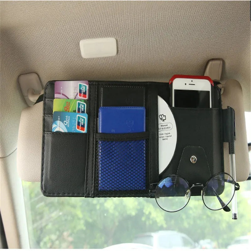 Beige car sun visor storage bag with seven open pockets, zip pocket, sunglasses clip, and pen holder on vehicle visor