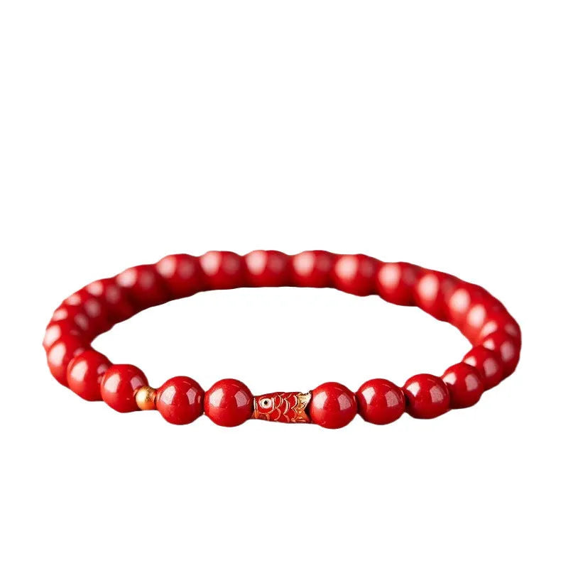Handmade natural cinnabar koi bracelet with gold balls on a bead, showing traditional Chinese style.