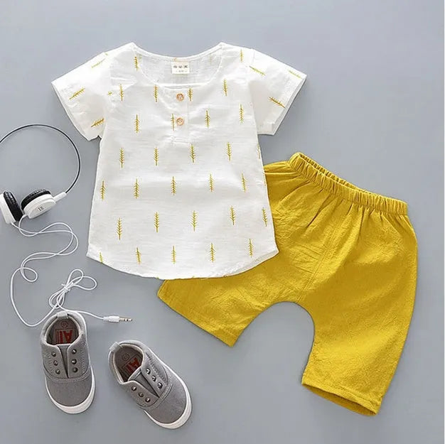 Baby boy wearing a blue crocodile print cotton t-shirt and matching blue shorts summer outfit set.