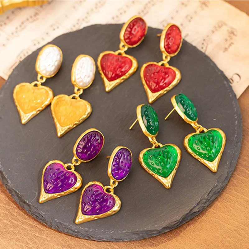 A pair of purple heart-shaped alloy stud earrings with a pleated oval texture and silver post.