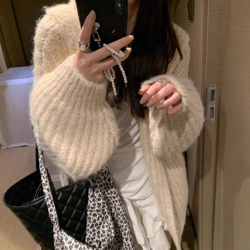 A woman wearing a thick, loose-fit, dark grey hooded sweater cardigan with a retro design.