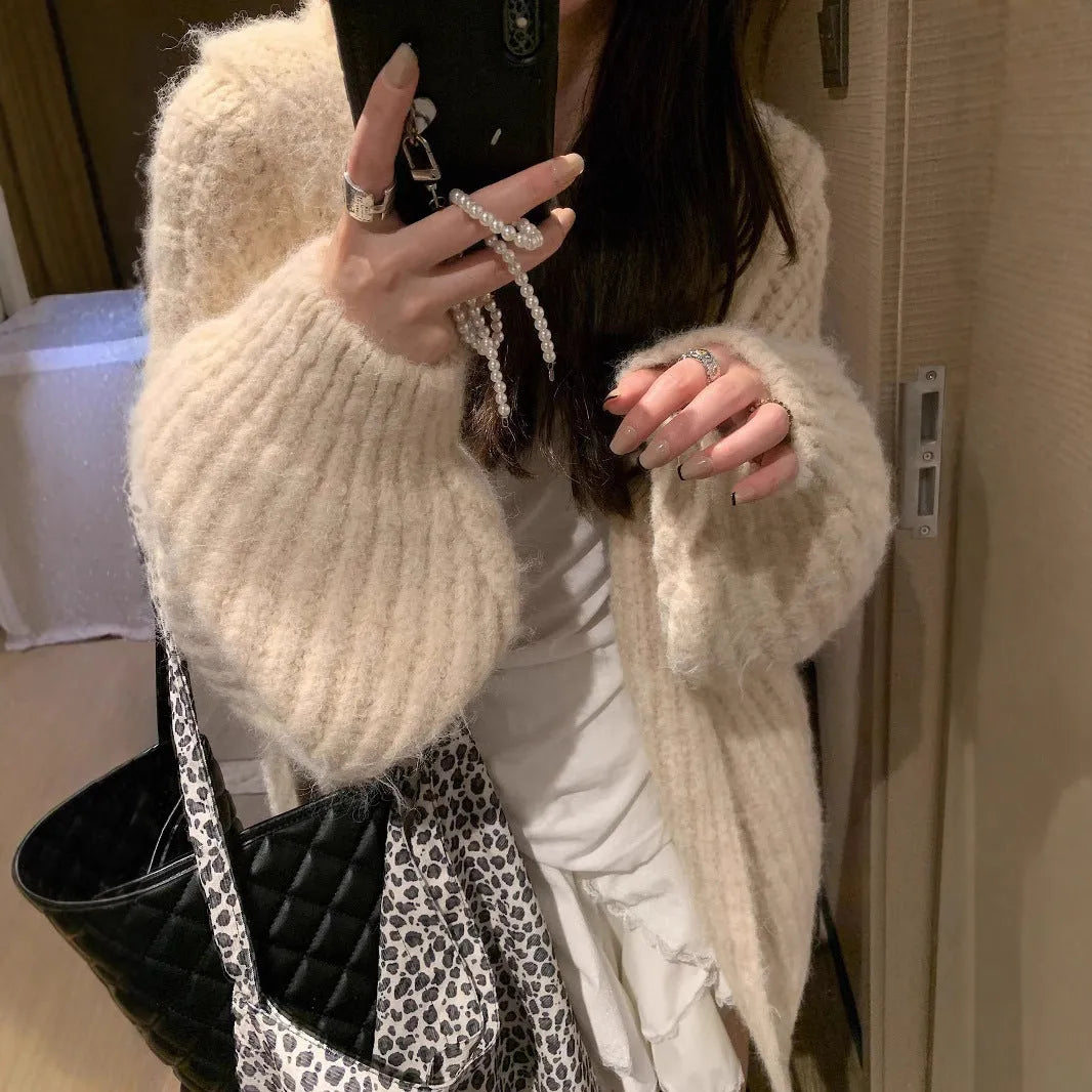 A woman wearing a thick, loose-fit, dark grey hooded sweater cardigan with a retro design.