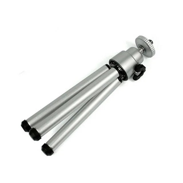 Compact mini desktop tripod with extendable aluminium legs and a black U-shaped phone clip attached.