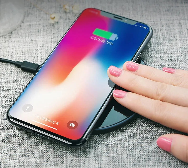 Black or white glass disc wireless charger on a surface, showing status light.