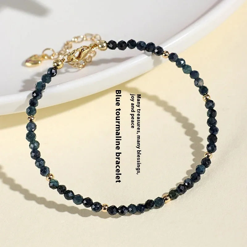 Close-up of a women's bracelet with 3mm blue tourmaline cut beads and silver-toned spacer beads on a wrist.
