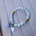 Natural green jade bracelet with a geometric shape and a hanging apple charm on a white background.
