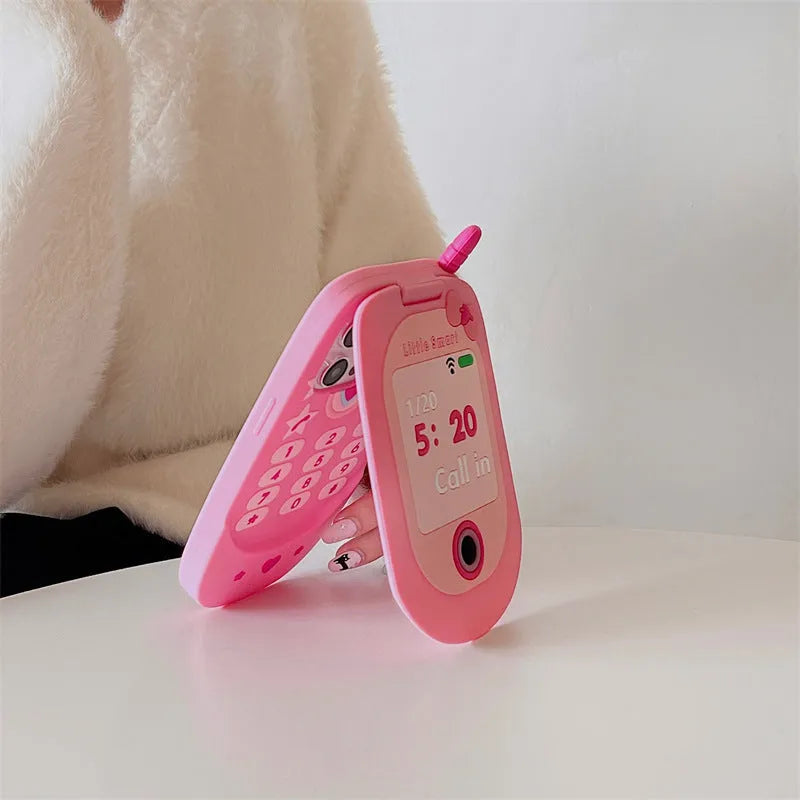 A light pink silicone iPhone case shaped like a flip phone with a built-in mirror on the front.