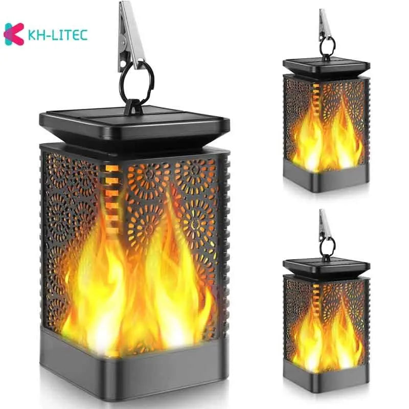 Set of four black solar-powered hanging torch lights with flickering flame LED effect in a garden setting
