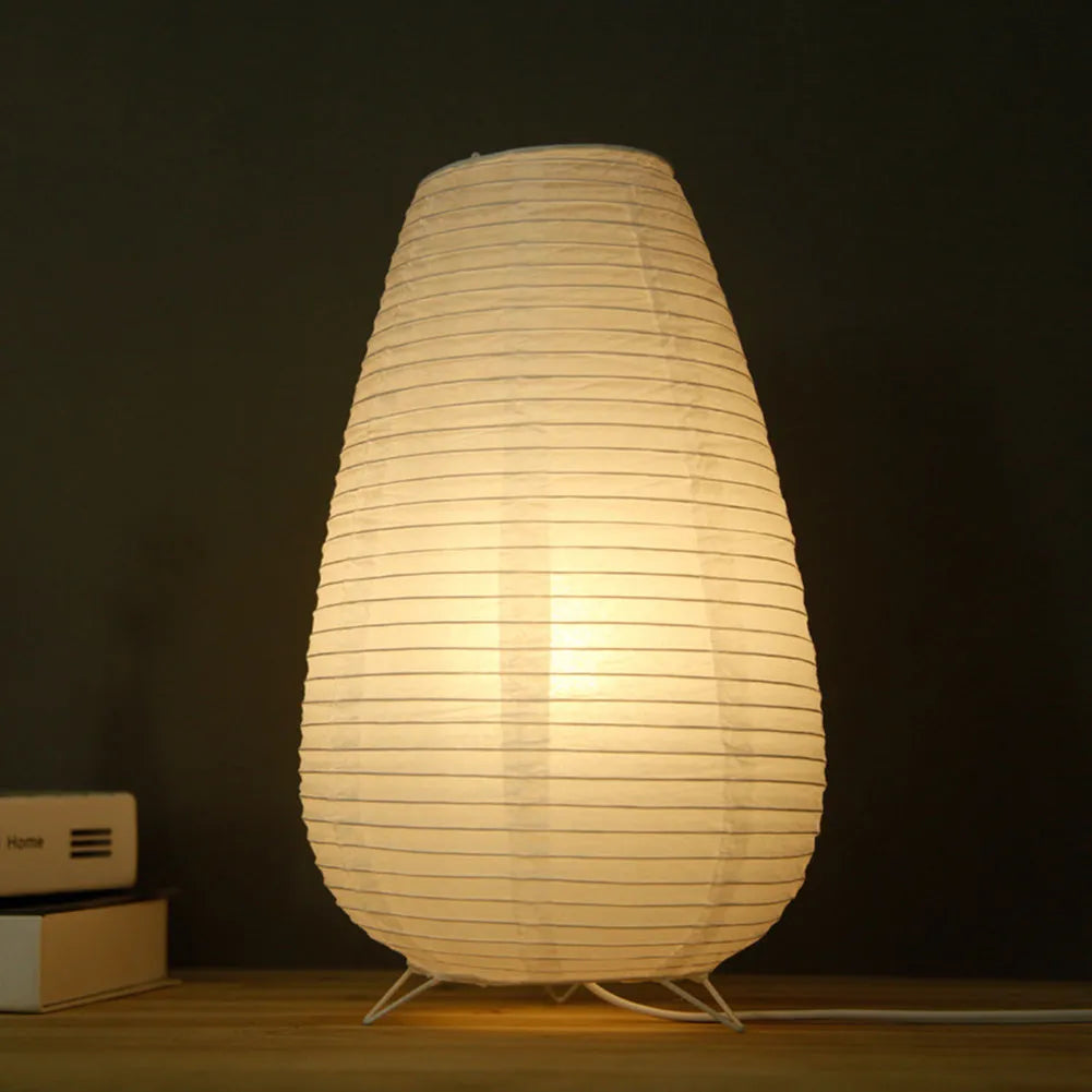 White handcrafted rice paper table lamp with either a circular or rectangular shade on a wooden desk.