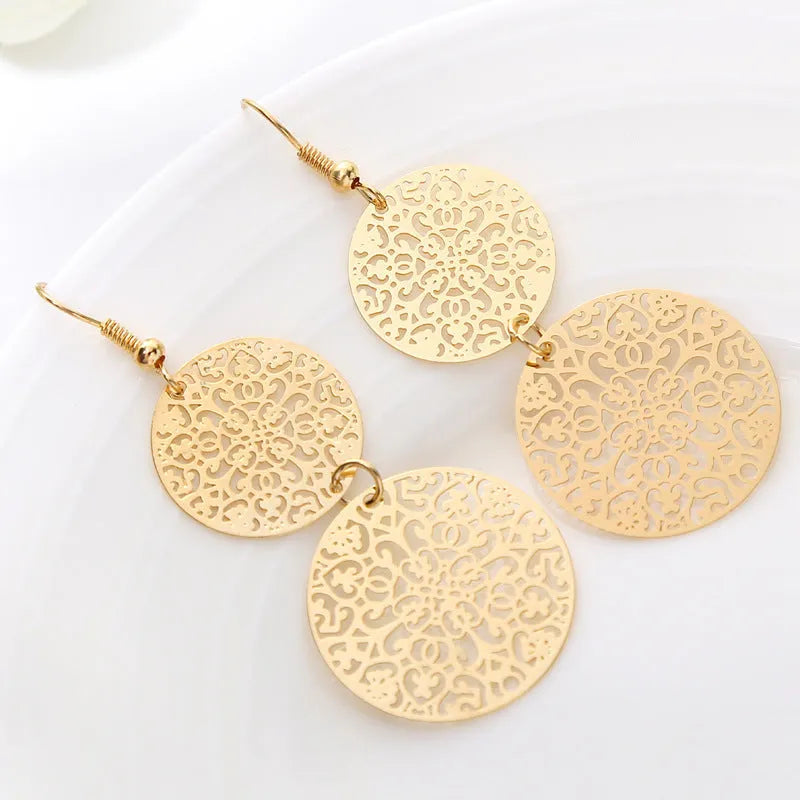 Women's round hollow gold drop earrings with dangle design on a light background
