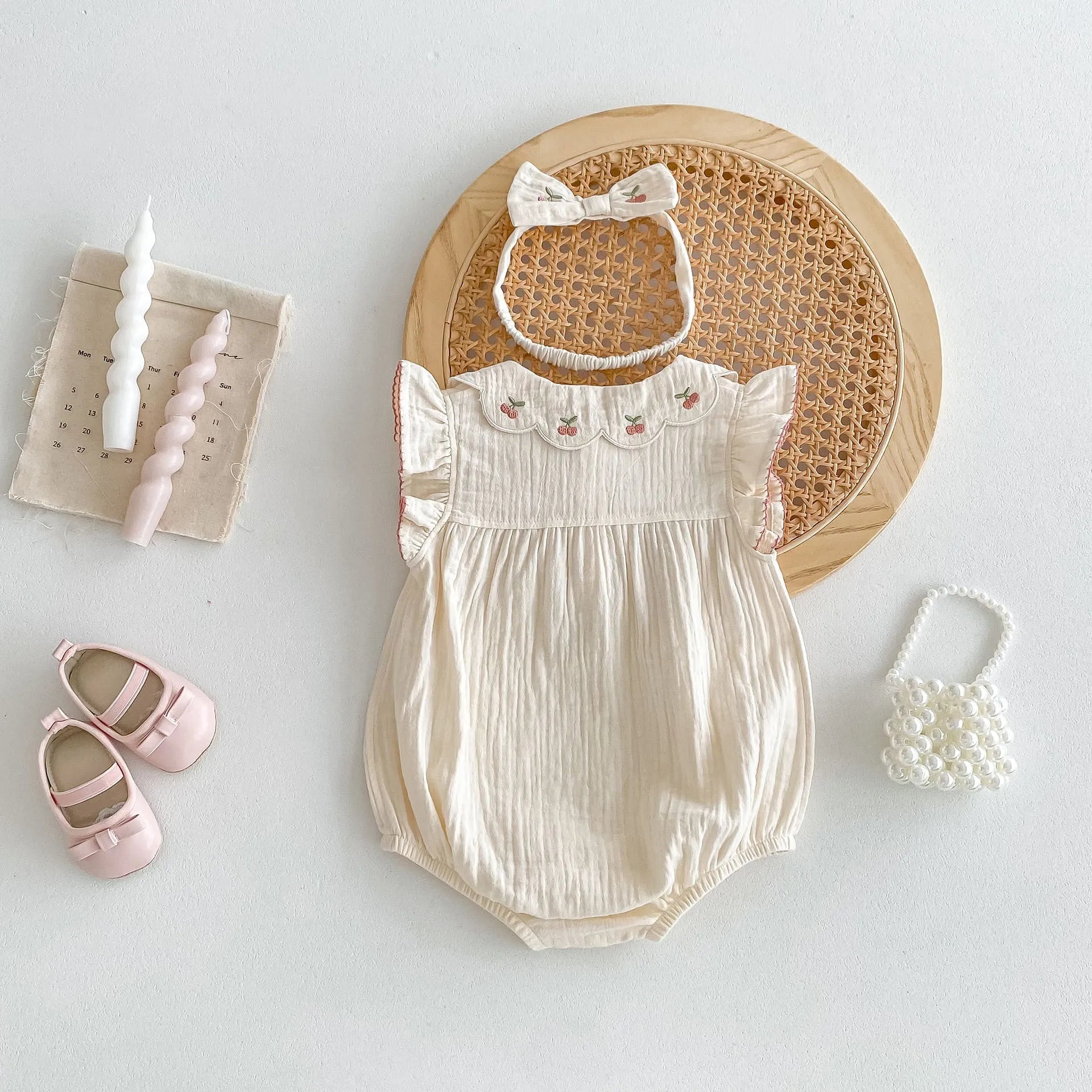 Apricot cotton double breasted sleeveless baby jumpsuit with matching hair band on white background