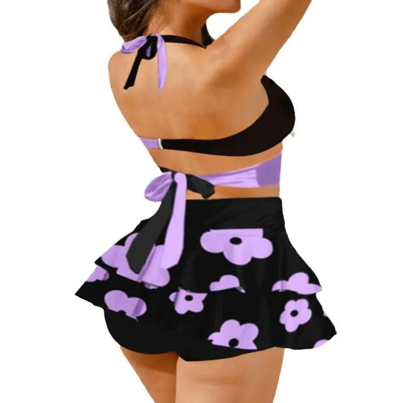 Purple and black women's bikini swimsuit set with lace-up details and a matching skirt.