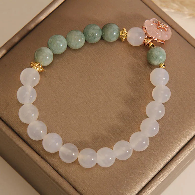 Women's white agate jade flower bracelet on a wrist, showing detailed floral carving.