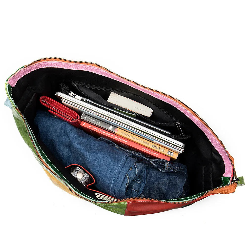 Brown cowhide leather travel bag with a long strap, shown next to a laptop and an A4 magazine for scale.