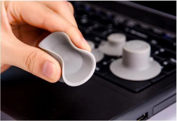 Grey plastic laptop cooling pad stand with four non-slip pads on a desk.