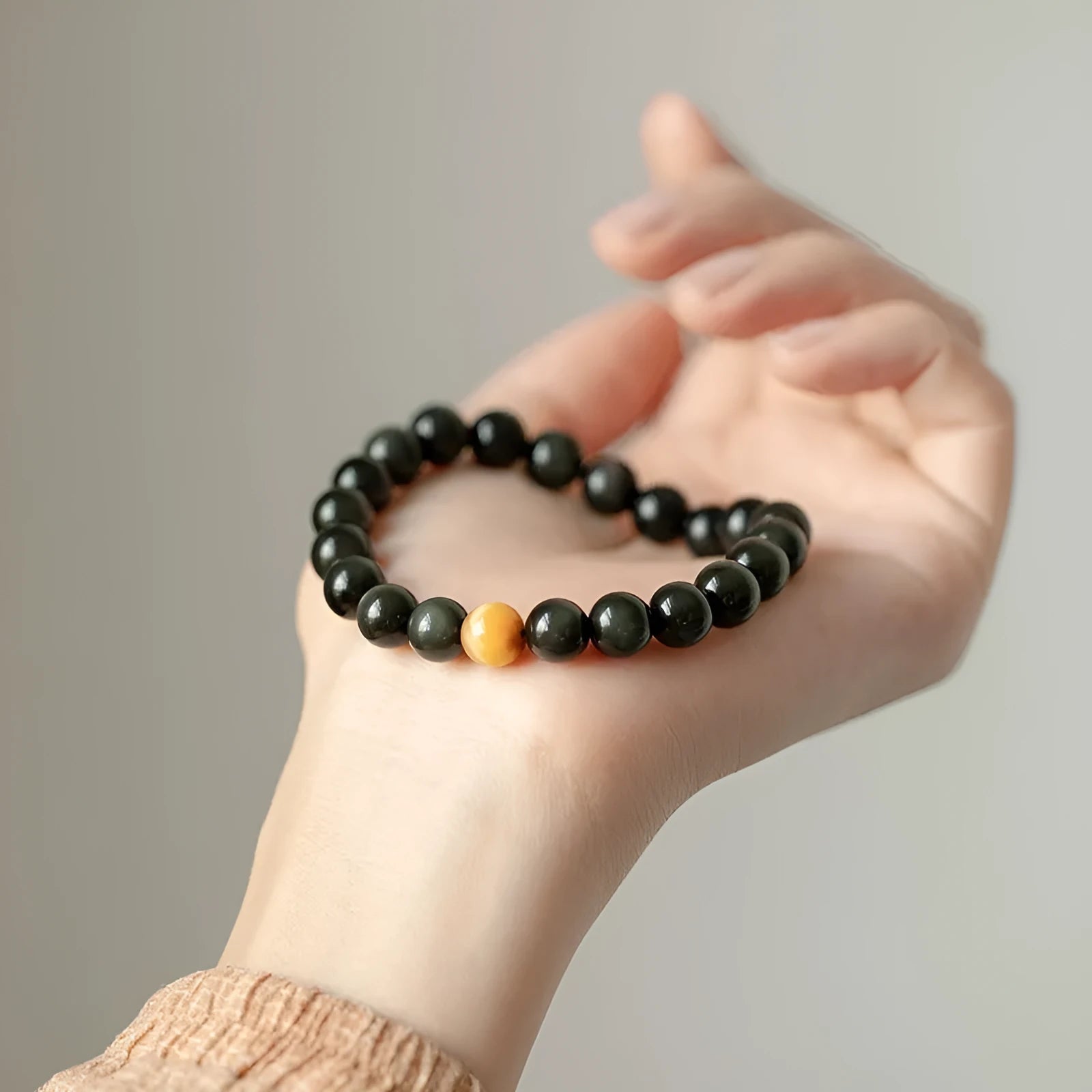 Black obsidian geometric bracelet with spherical beads on a wrist, showing unisex Korean style.