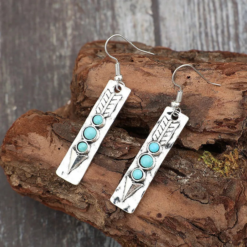 Silver geometric earrings with turquoise detail on white background