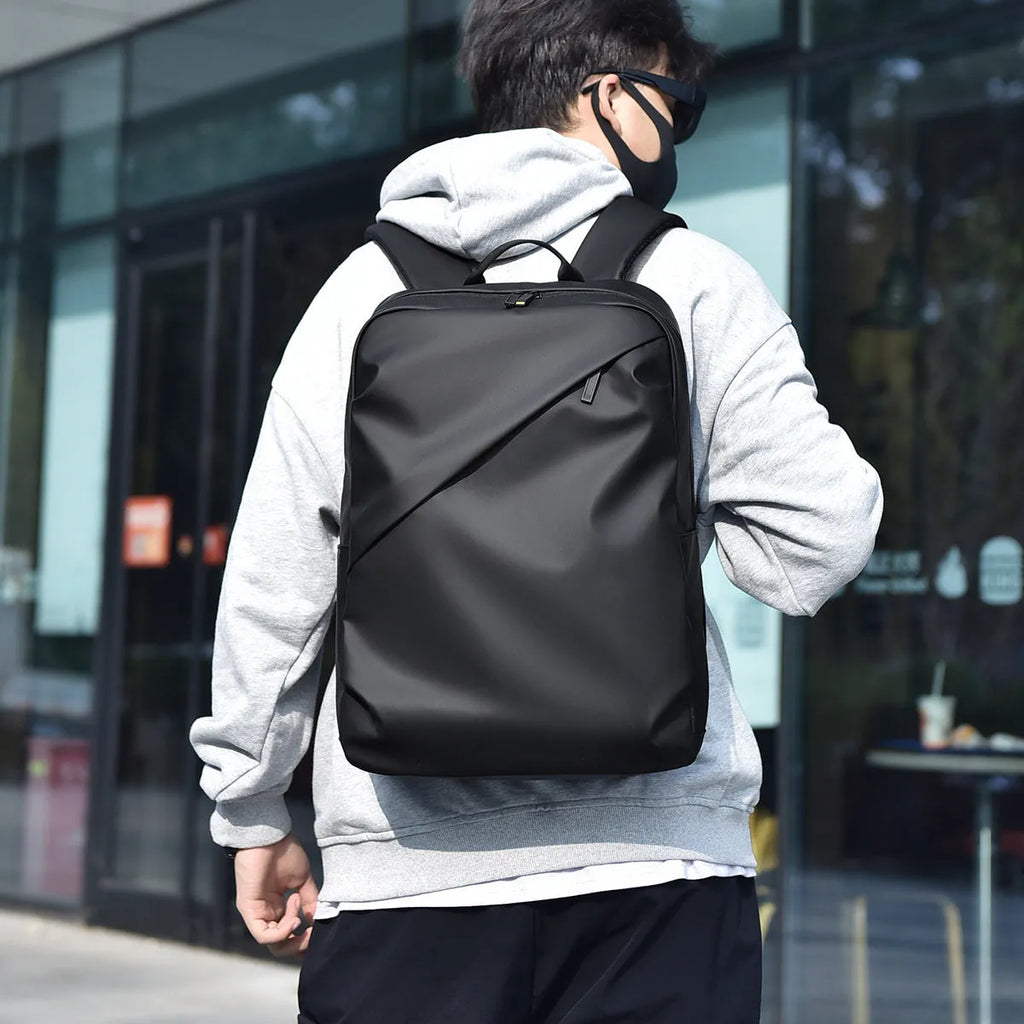 Men's large waterproof black PU leather backpack with laptop compartment on a grey background.