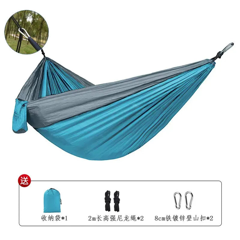Blue nylon parachute cloth camping hammock hung between two trees outdoors