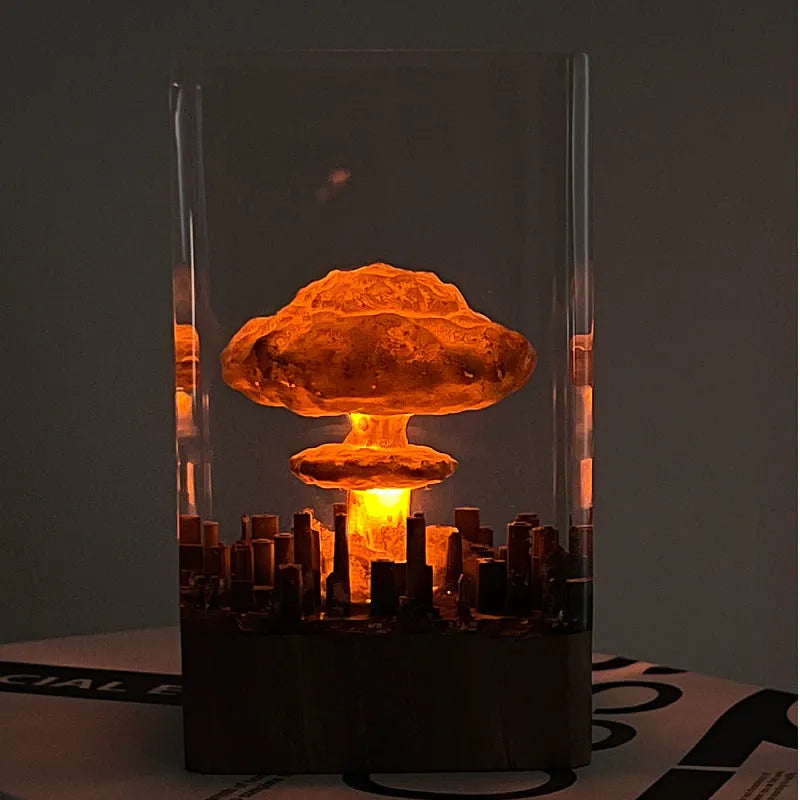 Small atomic bomb mushroom cloud shaped resin night lamp decoration in two colour variants on a dark surface.