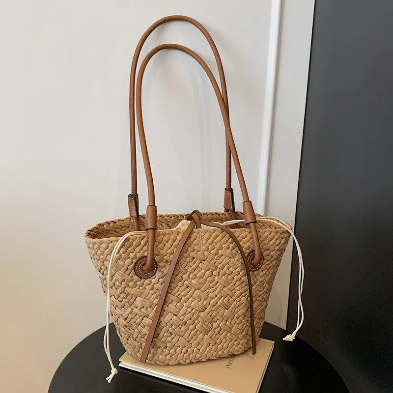 A retro-style horizontal square woven bag in milky white, shown being carried by hand.