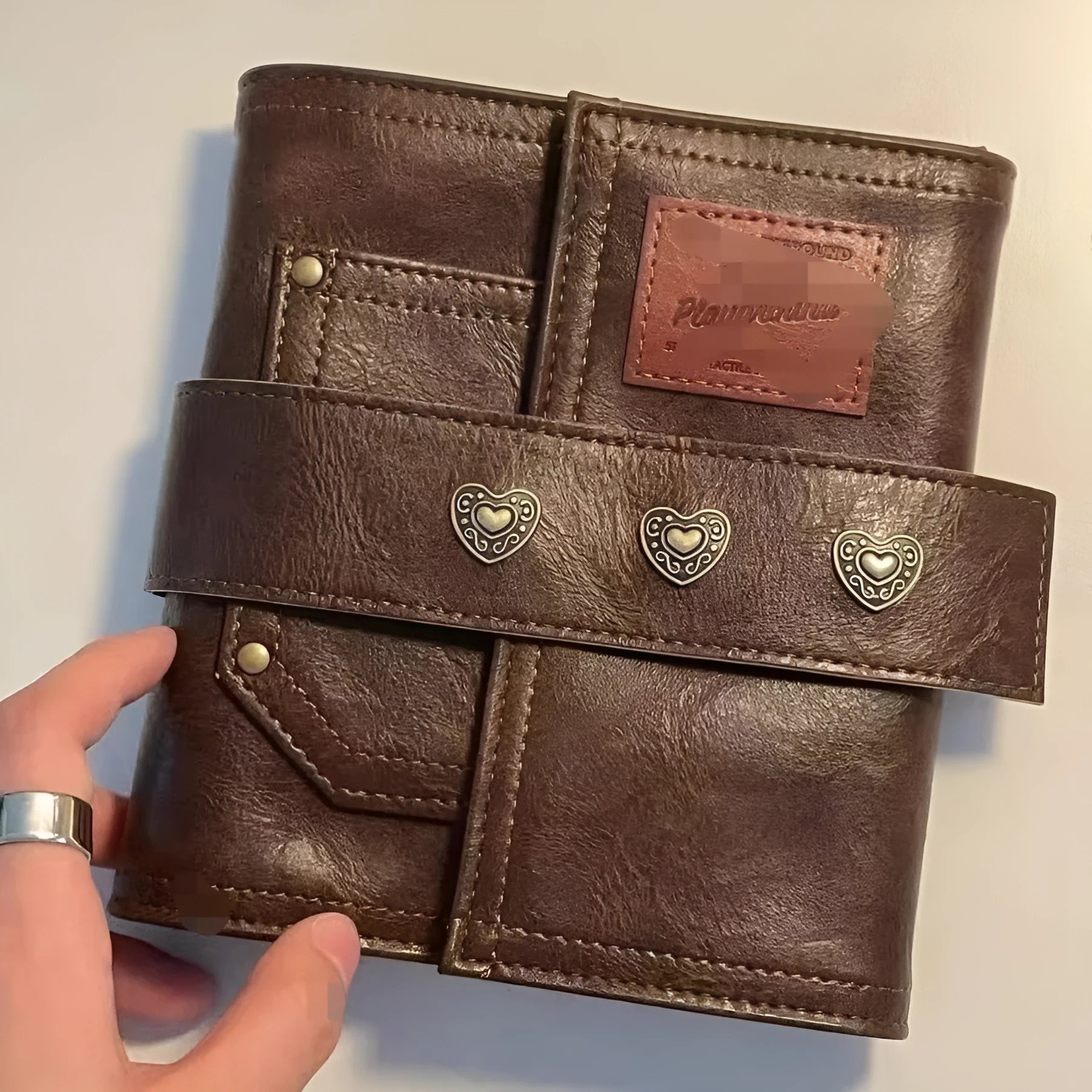 Brown A7 retro notebook with buckle closure showing loose-leaf binding and raw wood pulp paper