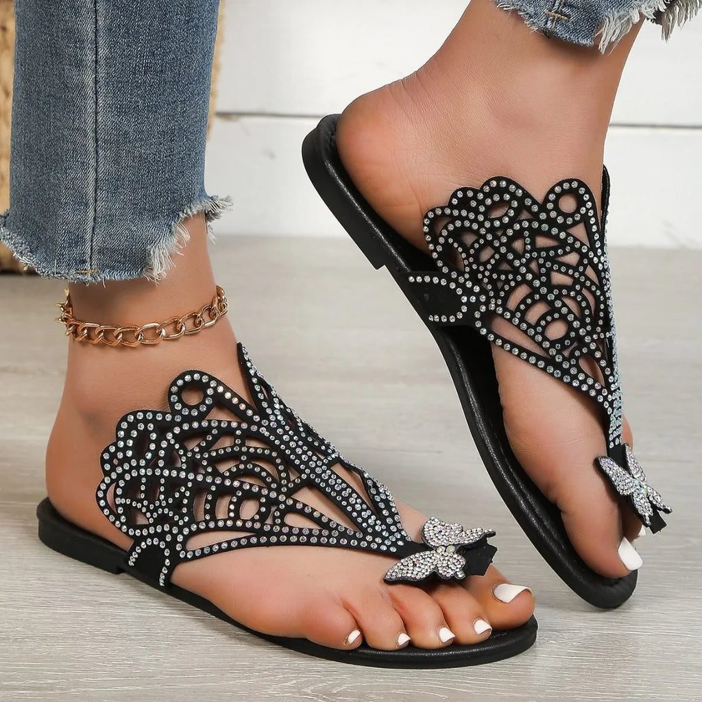 Women's black slip-on sandals with rhinestone decoration and a flip-toe, hollow design.