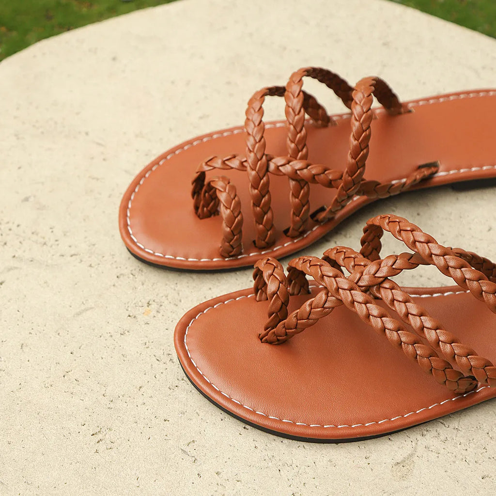 Women's brown woven clip-toe flat sandals on a light background.