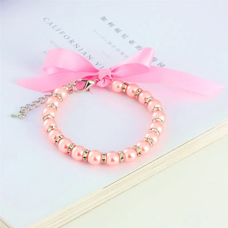 Small dog wearing adjustable pearl and rhinestone necklace with bow in blue colour