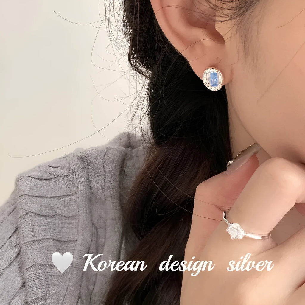 Sterling silver earrings with heart-wrapped oval blue diamond design and electroplated finish