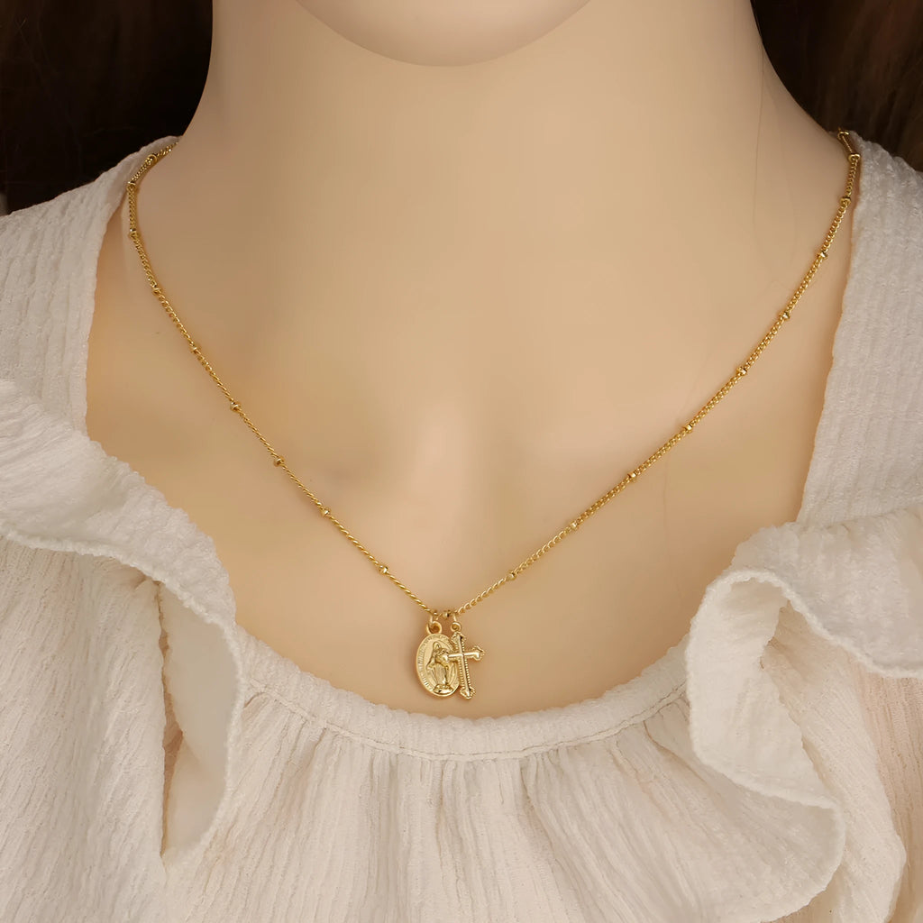 Gold coloured geometric cross necklace with a Virgin Mary ornament on a chain.