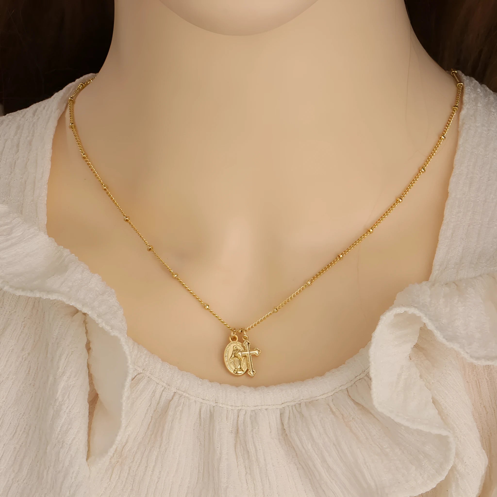 Gold coloured geometric cross necklace with a Virgin Mary ornament on a chain.