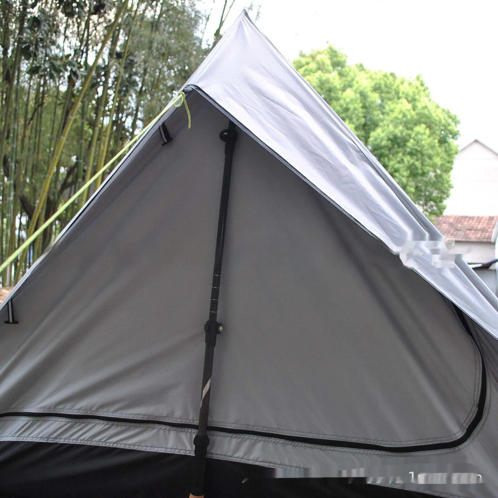 Brown ultralight A-frame hiking tent pitched with hiking poles in an outdoor setting