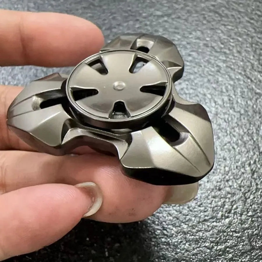 Alloy metal fingertip gyro decompression toy in gun metal colour, spinning on a surface.