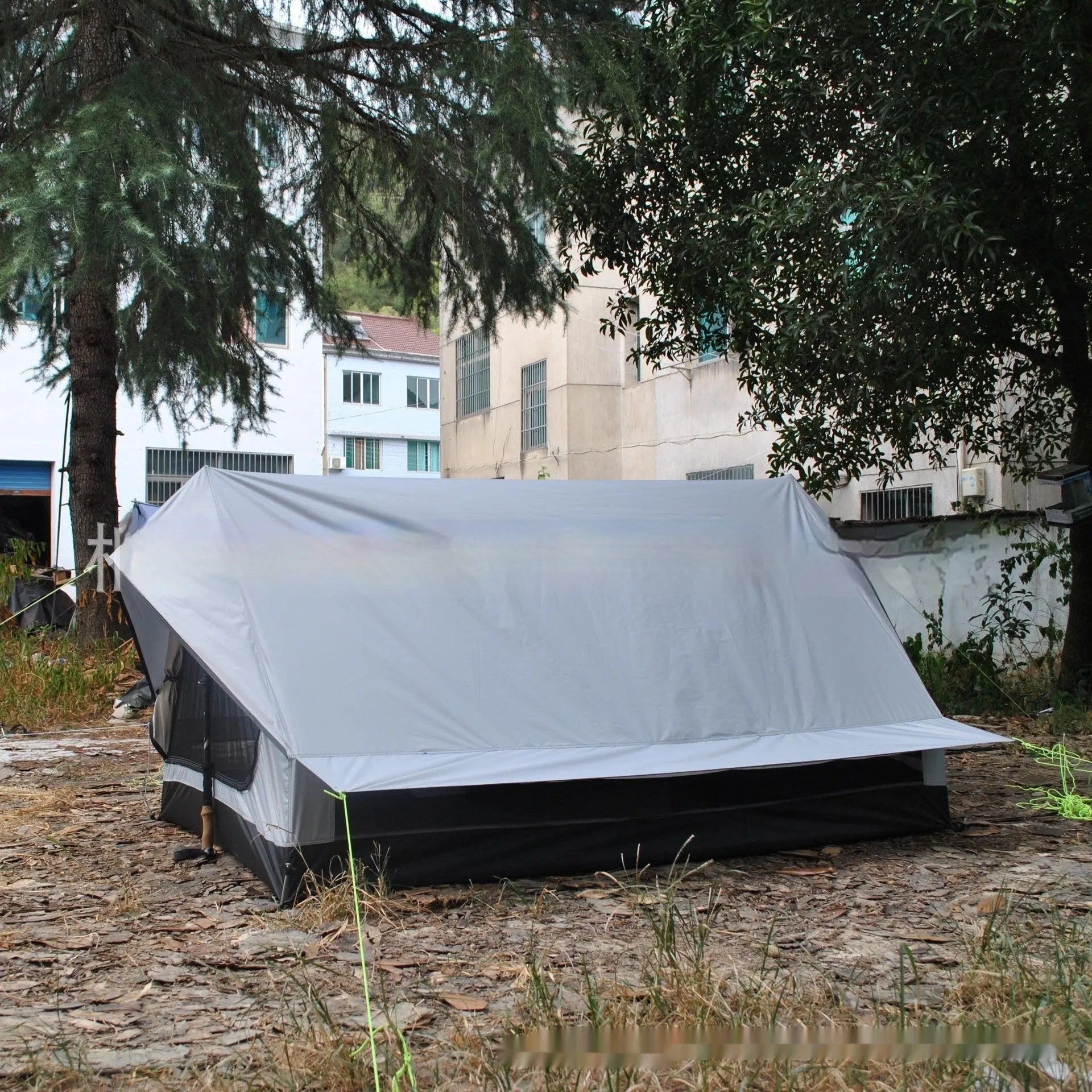 Brown ultralight A-frame hiking tent pitched with hiking poles in an outdoor setting