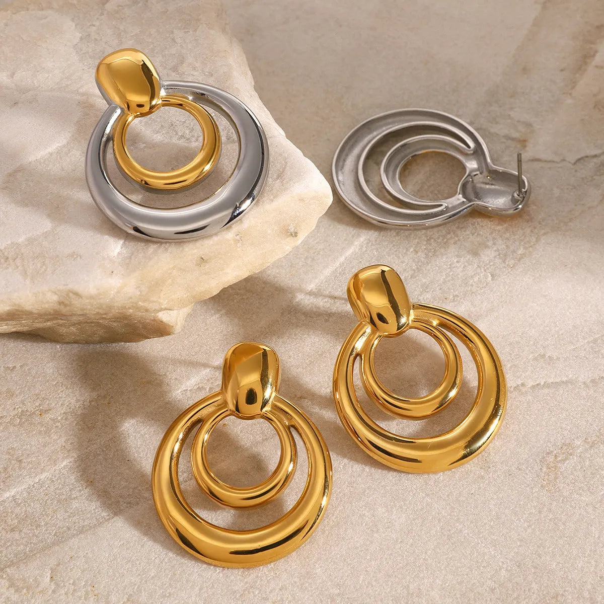 Golden round geometric stud earrings with hollow double layer design on white background