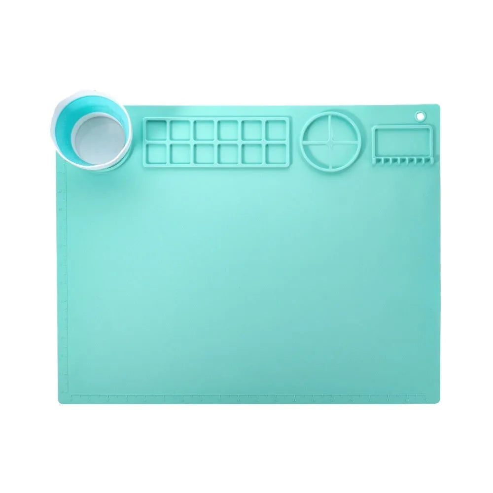 Light blue silicone painting mat measuring 50 by 40 centimetres on a wooden table.