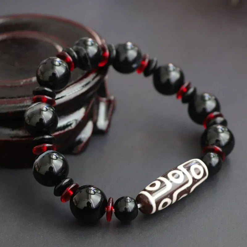 Hand-woven black agate Dzi bead bracelet with chalcedony detail on a wrist.