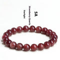 A stretch bracelet with round, pink strawberry quartz beads on an elasticated cord, shown in different size options.
