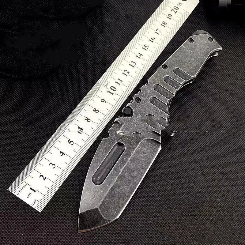907 style outdoor folding knife with D2 steel blade, 9 cm blade, black handle, closed position on grey background