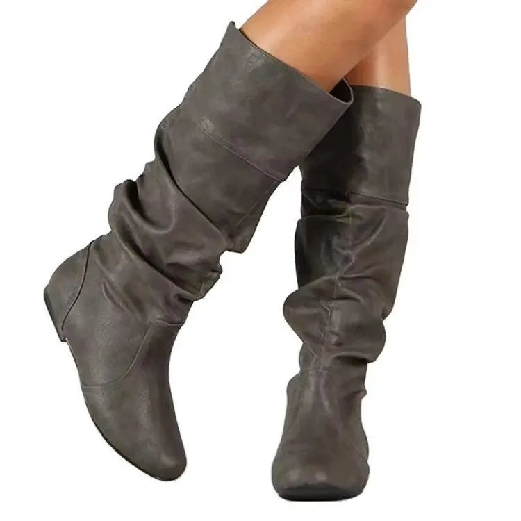 Women's black slip-on flat boots with round toe and high cylinder shaft on a non-slip rubber sole.