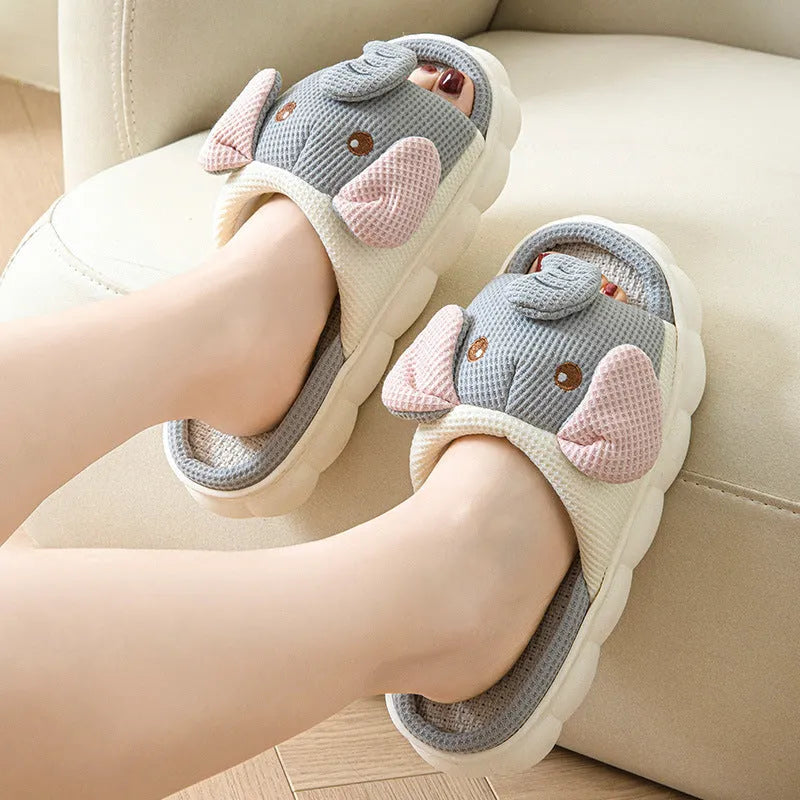 A pair of elephant grey open-toe linen slippers for couples on a plain background.