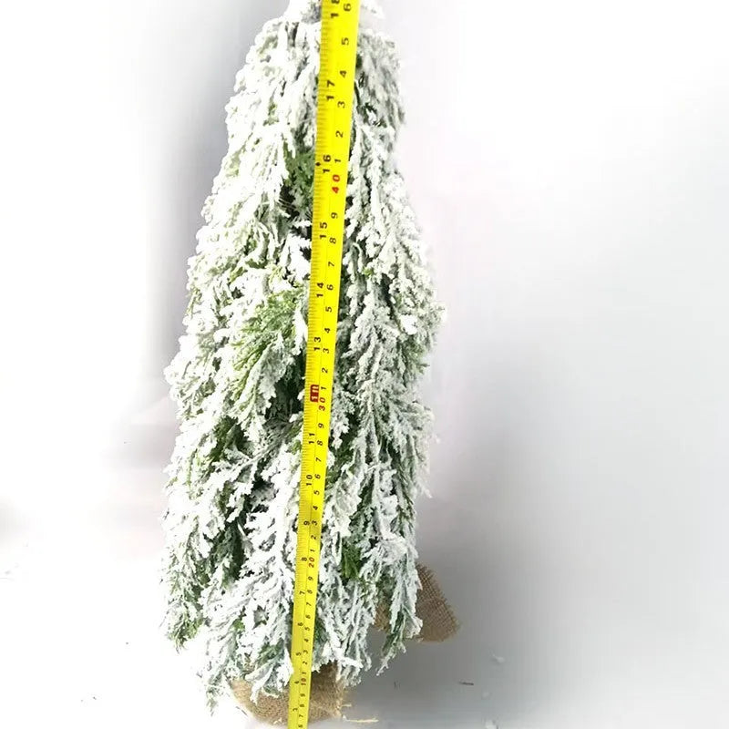 Small 24-inch frosted artificial Christmas tree with LED lights on a desktop.