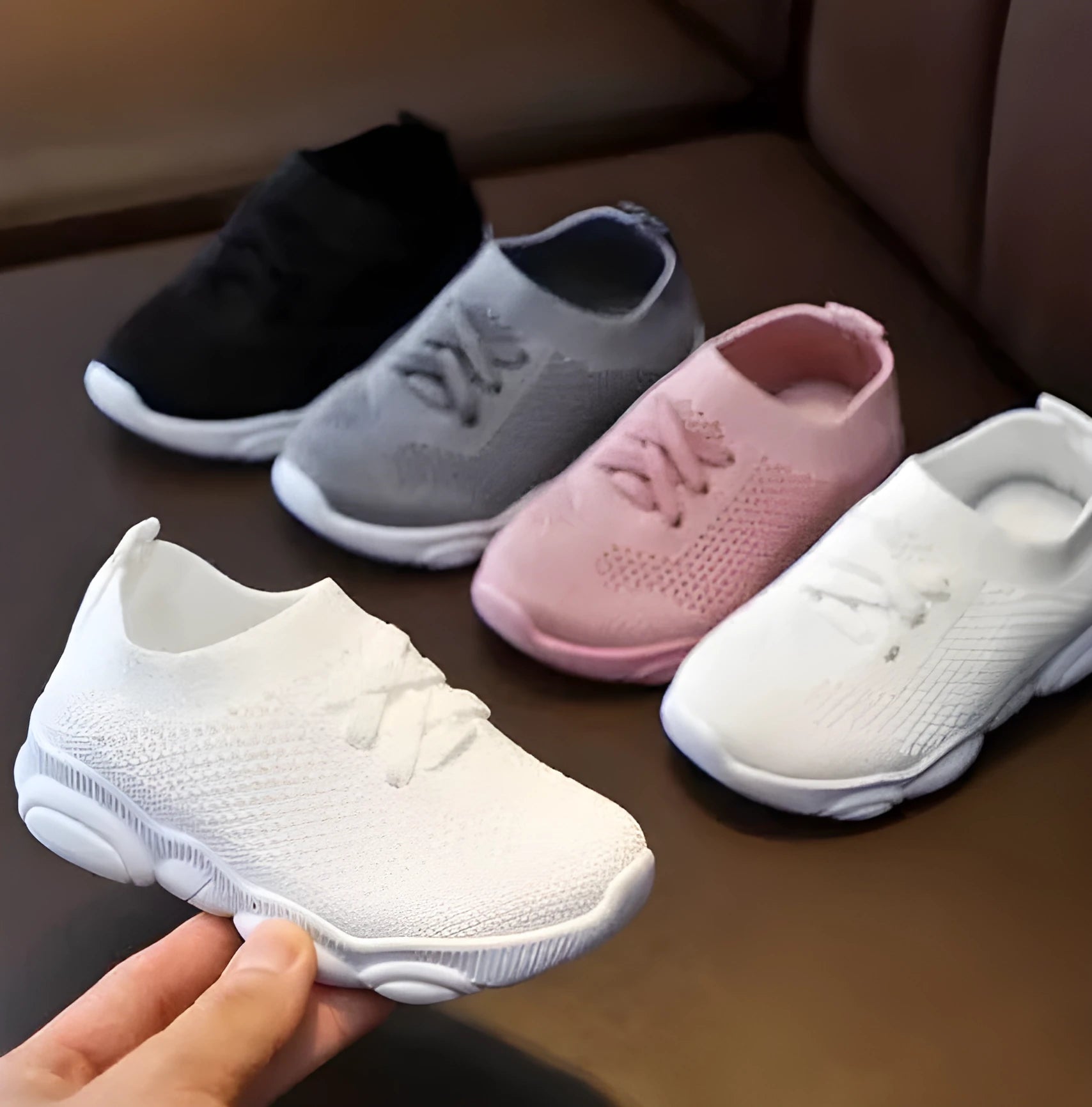 Children's white fabric lazy slip-on shoe with a non-slip rubber sole on a wooden floor.