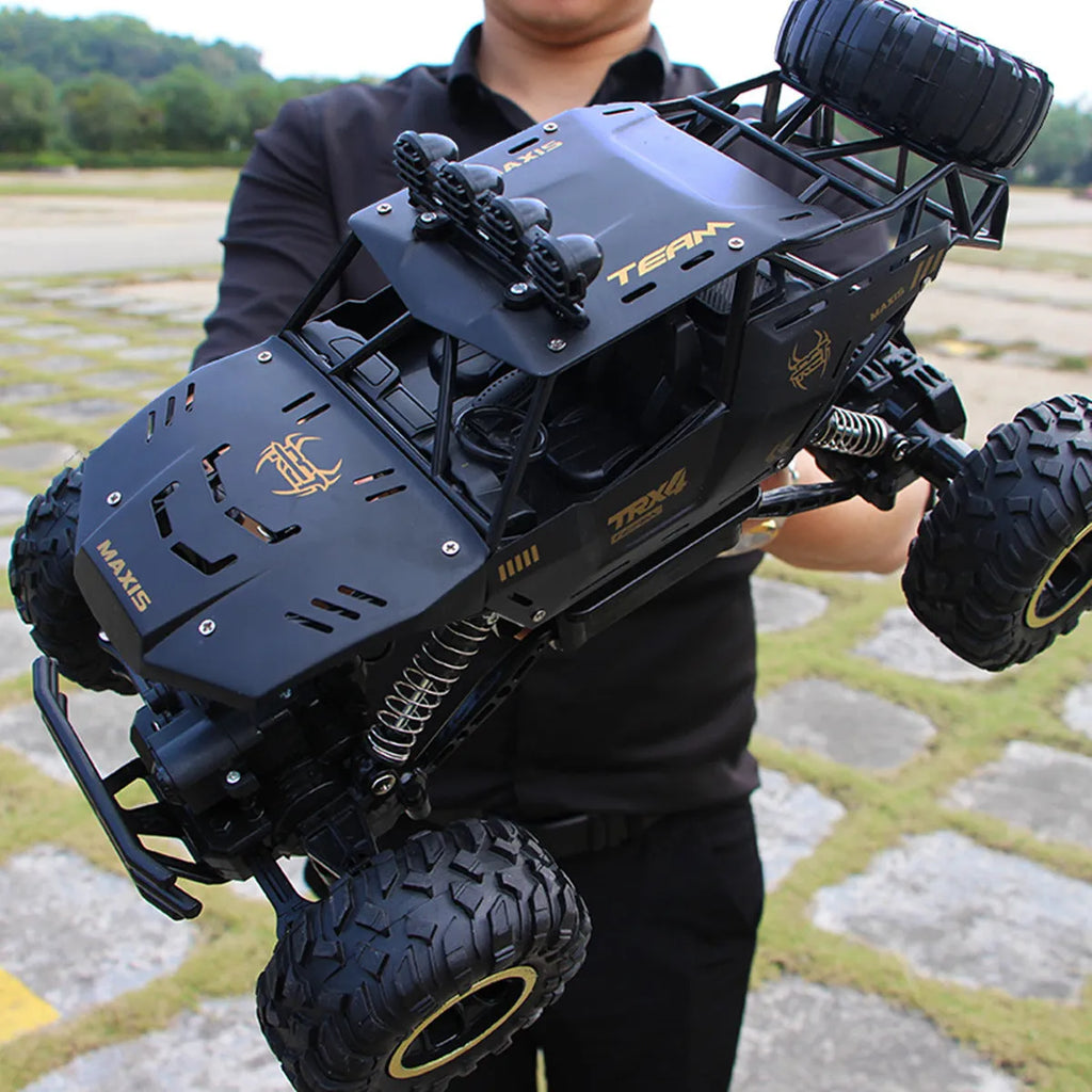 Black and silver remote control off-road car on rough terrain showing four-wheel drive and climbing capability.