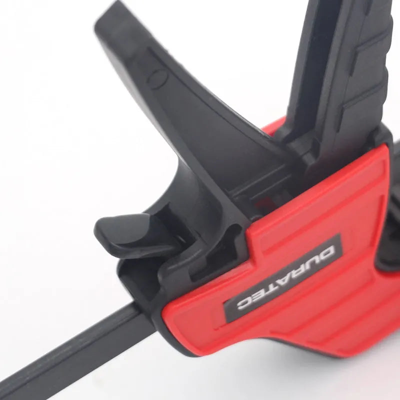Black plastic woodworking toggle clamp with quick-release mechanism and soft rubber protective pads